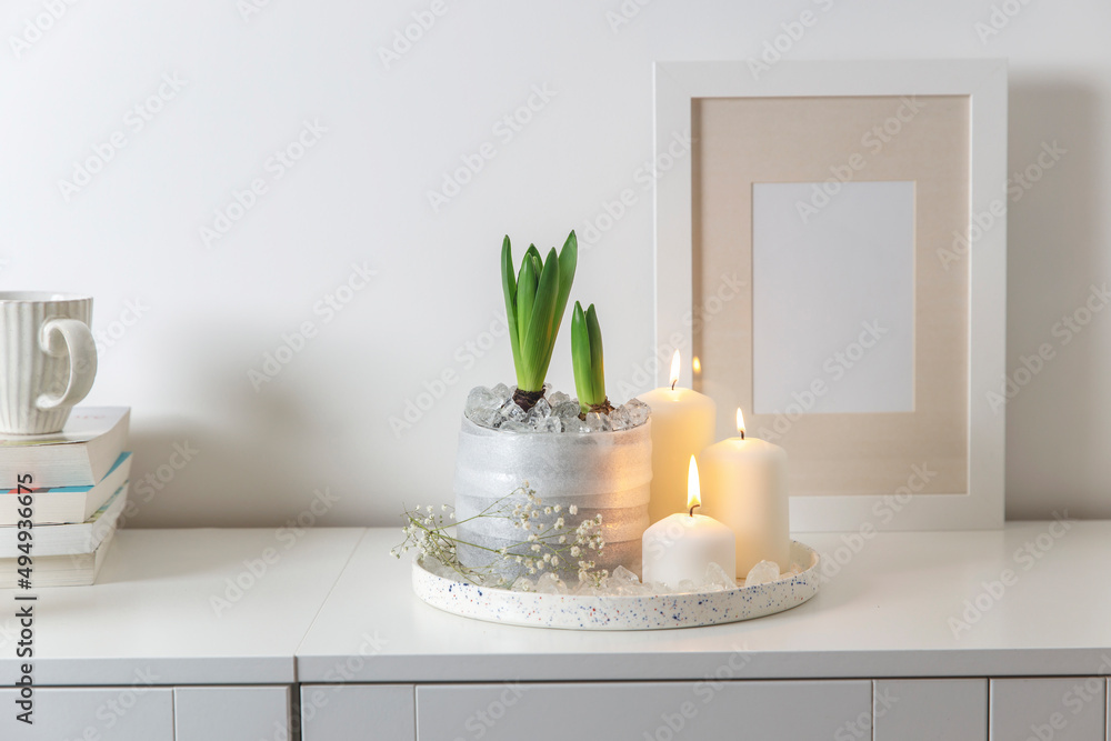 Unblown hyacinths with burning candles on a wooden vintage tray. Palm tree shadow on the wall. Home decoration for spring Unblown hyacinths with burning candles on a wooden vintage tray. Palm tree shadow on the wall. Home decoration for spring