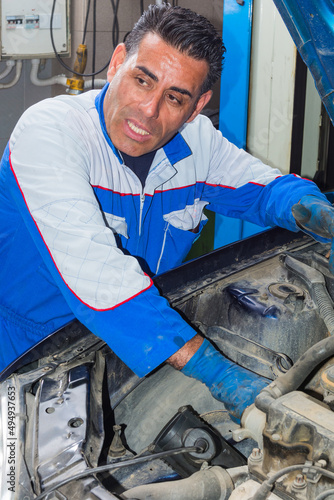 Auto mechanic working on car engine in mechanics garage - Repair service. authentic close-up shot photo