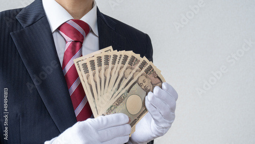 白手袋をはめたスーツ姿の男性。日本円の1万円札を数える│買取り査定イメージ photo