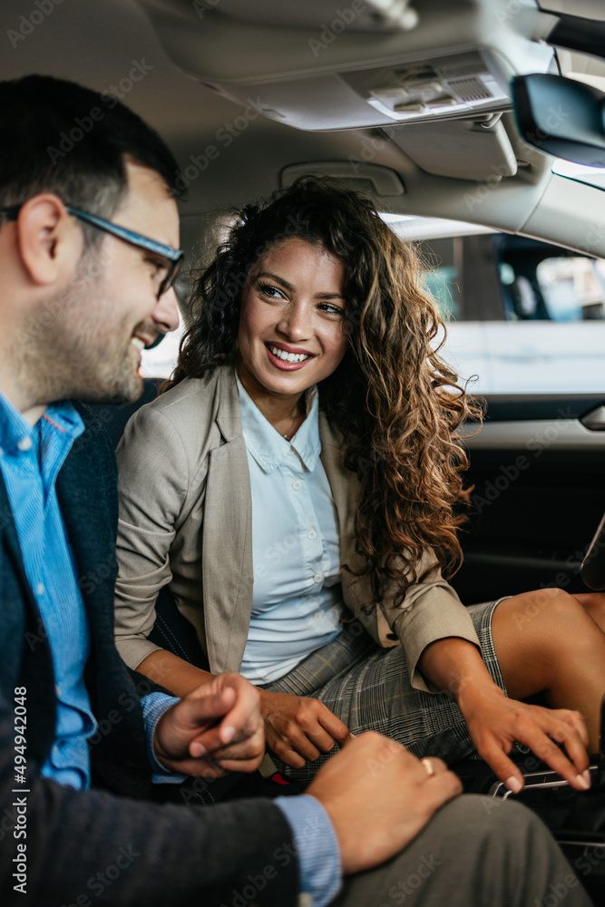 Happy middle age couple enjoying while choosing and buying new car at showroom. They are sitting inside of car. Happy middle age couple enjoying while choosing and buying new car at showroom. They are sitting inside of car.