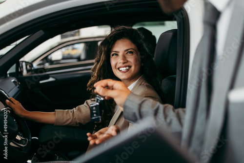 Фотография Happy and beautiful middle age business woman buying new car at showroom