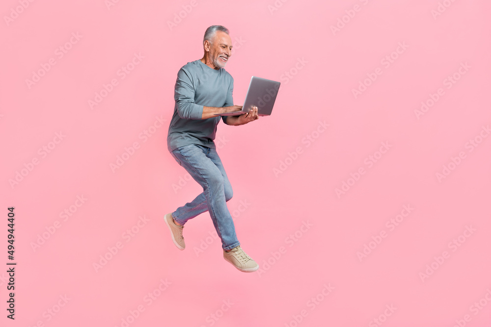 Photo of charming retired man wear grey shirt jumping chatting gadget empty space isolated pink color background Photo of charming retired man wear grey shirt jumping chatting gadget empty space isolated pink color background
