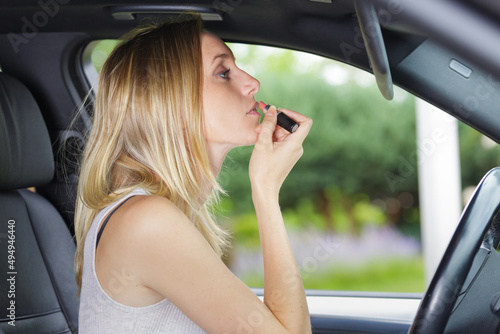 woman making up her lips with red lipstick in car © auremar