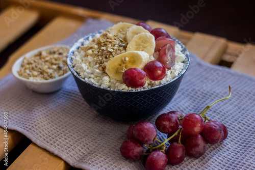 A plate of cottage cheese with granola, muesli, oatmeal, grapes and banana. Protein diet breakfast. Healthy and delicious food for breakfast. High quality photo