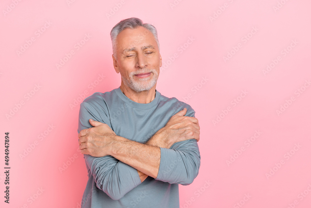 Photo of dreamy adorable retired man wear grey shirt hugging himself closed eyes isolated pink color background Photo of dreamy adorable retired man wear grey shirt hugging himself closed eyes isolated pink color background