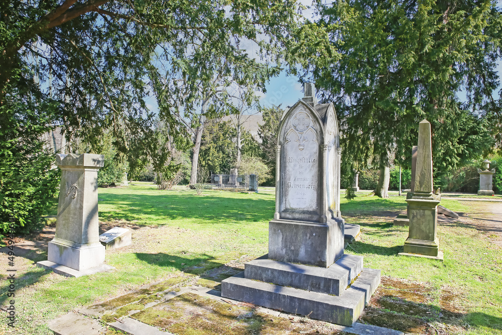 Düsseldorf (Golzheimer Friedhof), Germany - March 21. 2022: View on path through ancient city cemetery with listed monumental tombstones Düsseldorf (Golzheimer Friedhof), Germany - March 21. 2022: View on path through ancient city cemetery with listed monumental tombstones