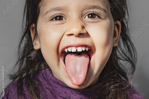 Close-up portrait of an emotional preschooler sticking out his tongue and showing grimaces