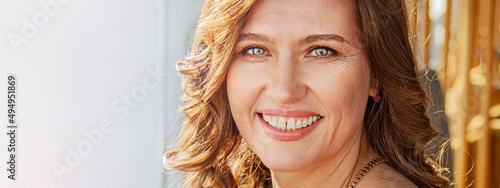 Portrait of an attractive mature woman smiling with happiness. A well-groomed and self-confident woman of 45-50 years old. Unusual green eyes, a great smile and healthy teeth.