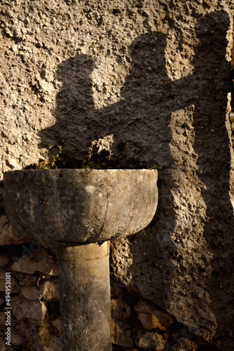 Vertical shot of an ancient stone holy water font outdoors under the sunlight photo