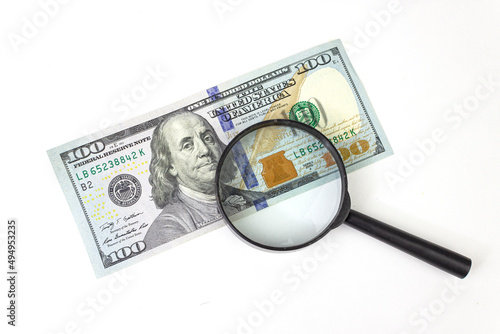 One hundred dollars through a magnifying glass close-up. Concept on the theme of checking money for authenticity.
