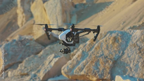 Drone flies on background rock. Modern technologies for shooting photos and videos from above. Golden hour
