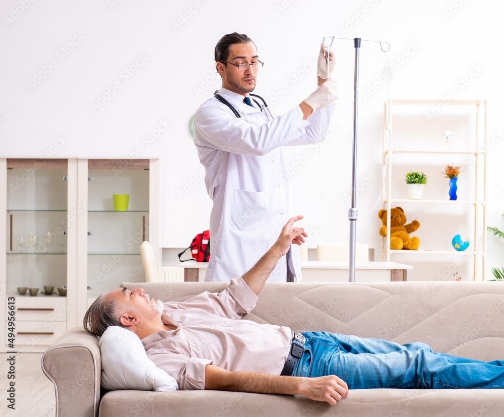 Obraz premium Young male doctor visiting old patient at home