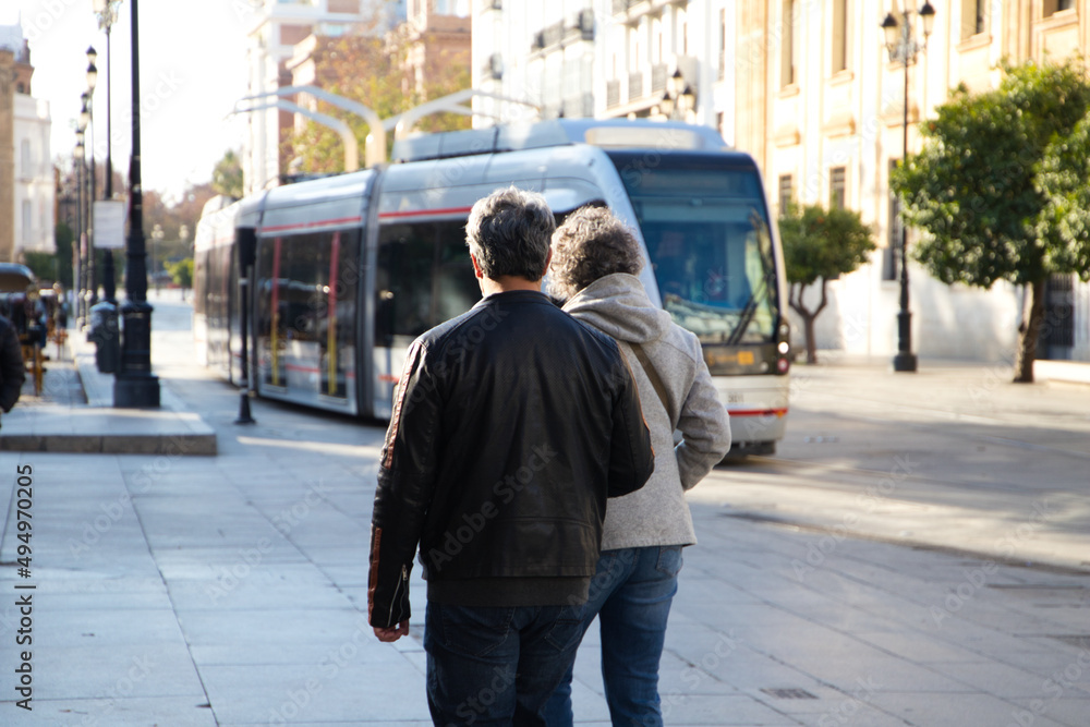 An adult couple on holiday are walking through a city. In the background you can see the tram. Concept of travel and holidays around the world.