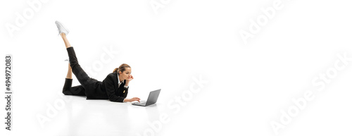 Photography Portrit of young businesswoman in official black suit lying on floor and typing