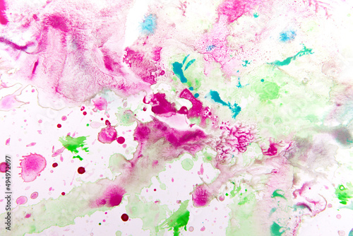 paints on a white sheet of paper. drops of pink, green, turquoise color. background and texture of watercolor paints.