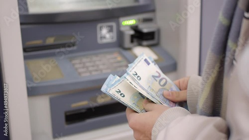 Close-up of female hands counting euro banknotes on ATM background. Banking service and cash withdrawal concept