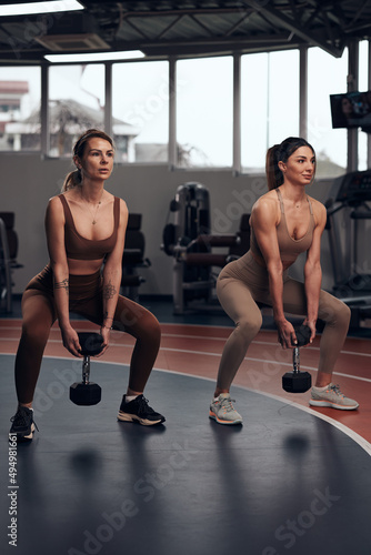 Pretty women working out in a gym. Adult ladies with beautiful shaped bodies.