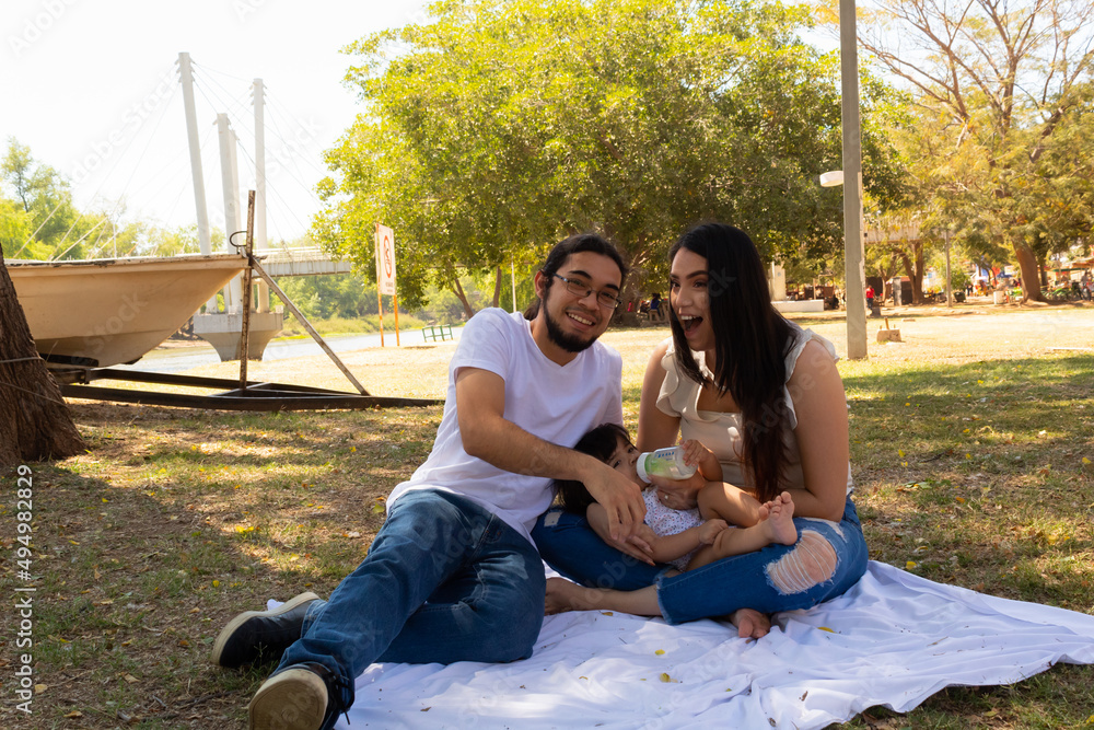 © Antonio Tanaka - Young Hispanic parents playing with their one year old baby in a park