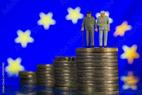 Miniature people old couple walking with a cane glass chess European Union Flag background. Concept of retirement pension strategy macro