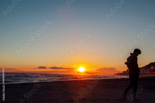 夕暮れの砂浜を歩く男性