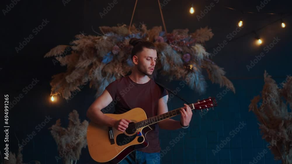 Male musician playing acoustic guitar. Guitarist plays classical guitar on stage in concert Handsome young hipster male guitar player perform private party Stylish long hair Medium shoot