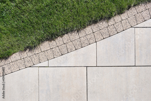 Combination of сoncrete slabs and paving tiles on the border with a lawn, top view. photo