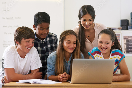 Using all the resources the internet has to offer. Shot of a group of schoolchildren using a laptop in class with their teacher.