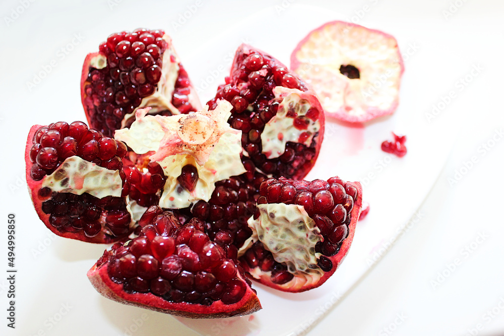 Cut ripe pomegranate into pieces on a white background Cut ripe pomegranate into pieces on a white background
