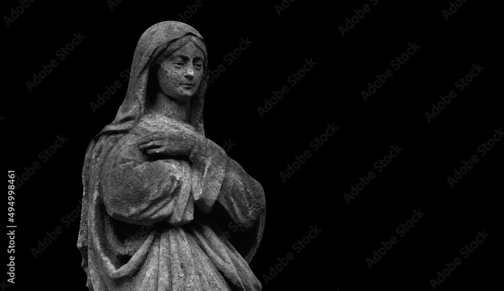 Virgin Mary. An ancient statue isolated on black background. Copy space for design.