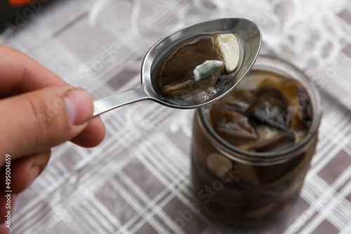 Botulism, food poisoning from canned foods concept. Opened Glass jar with homemade pickled mushrooms. Spoiled blackened forest mushrooms photo