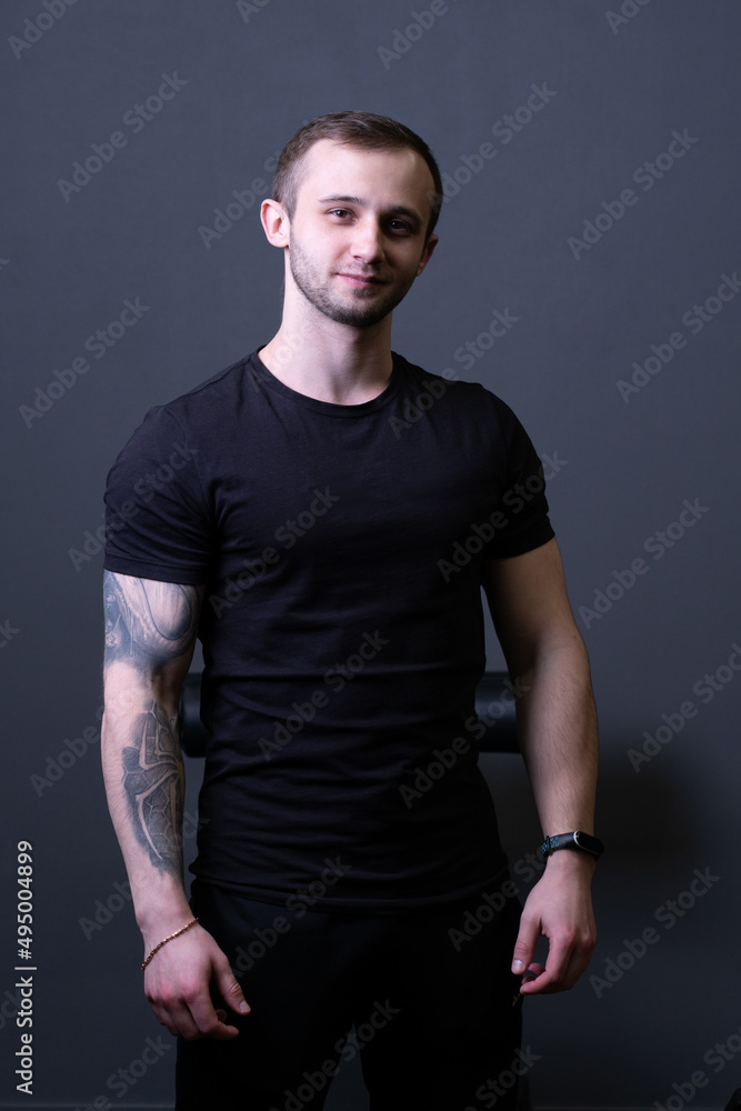 A guy standing in a black T-shirt is a beautiful sexy athlete handsome black man shirt blank, for one chest for caucasian for athletic people, torso sporty. Macho gorgeous biceps, arms adult