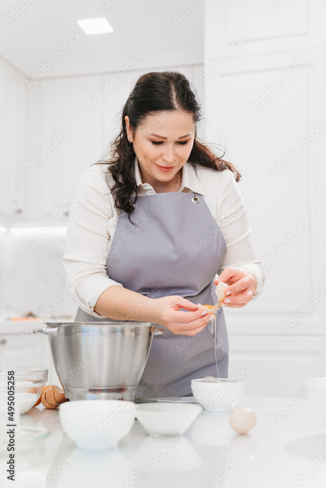 A woman breaks an egg and separates yolks from proteins