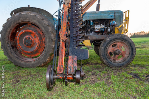 An antique cutter bar hedge trimmer mounted on a vintage tractor photo