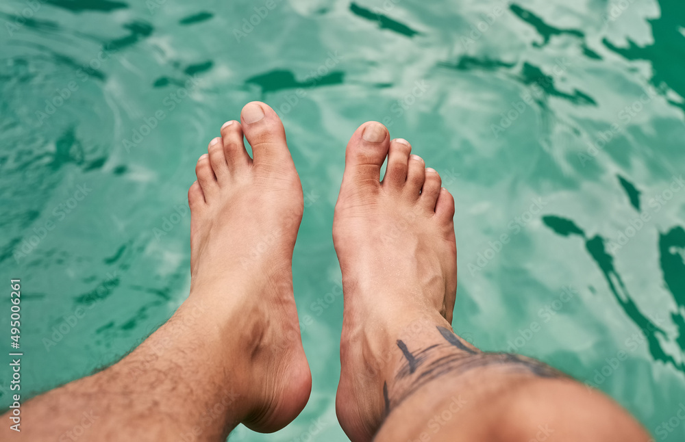 Getting a feel for the water. High angle shot of a mans feet above the water. Getting a feel for the water. High angle shot of a mans feet above the water.