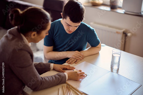 Foto Man with down syndrome having individual education class with is tutor at home