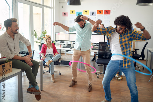Fototapeta A group of employees is having fun while playing with hula-hoop in the office