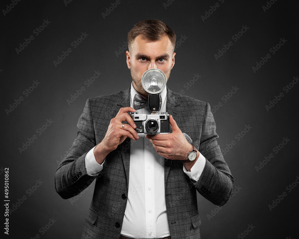 Portrait of an emotional handsome man holding a retro camera on a dark background. Flyer for advertising. Photography Profession Concept
Portrait of an emotional handsome man holding a retro camera on a dark background. Flyer for advertising. Photography Profession Concept