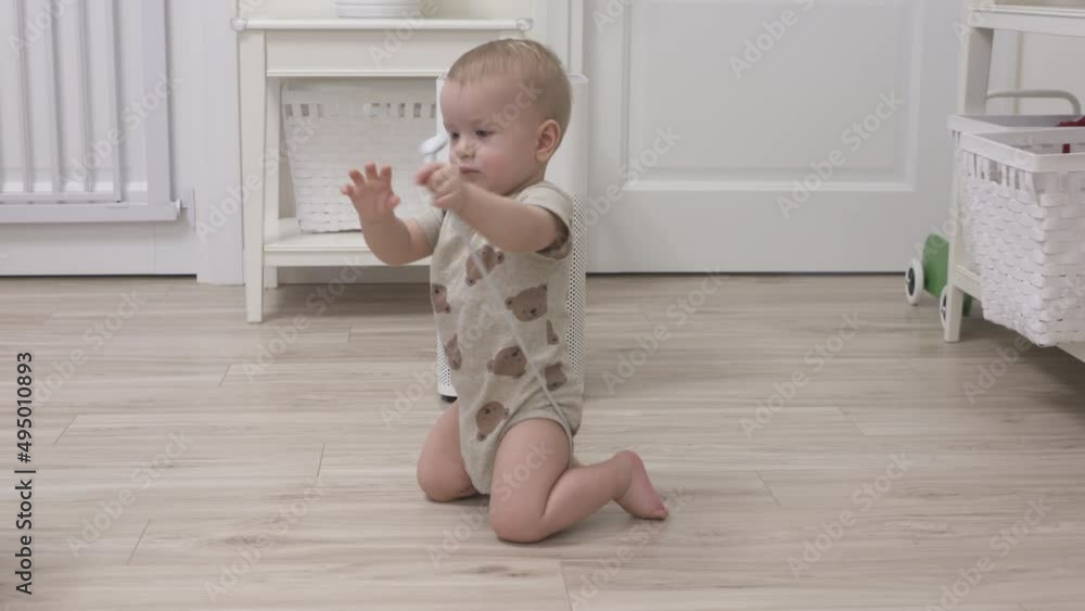 Toddler playing with electric wire on floor at living room, 1 year old infant holding the electric cord of air purifier, risky objects around the house for baby. High quality 4k footage Toddler playing with electric wire on floor at living room, 1 year old infant holding the electric cord of air purifier, risky objects around the house for baby. High quality 4k footage