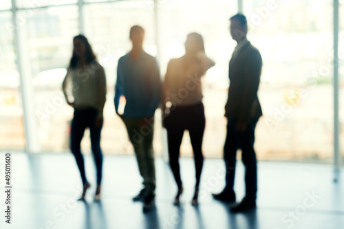 Even strong teams lose focus sometimes. Defocussed shot of a group of businesspeople brainstorming together in front of a window in the office.