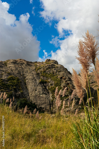 Macizo de piedra con vegetación de montaña, cielo azul con nubes. Sierras de Córdoba