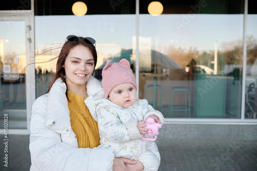 Mother holding baby smiling to camera. Real life authentic casual mom looking to camera holding