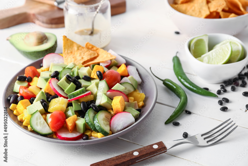Bowl of delicious Mexican vegetable salad on light wooden table