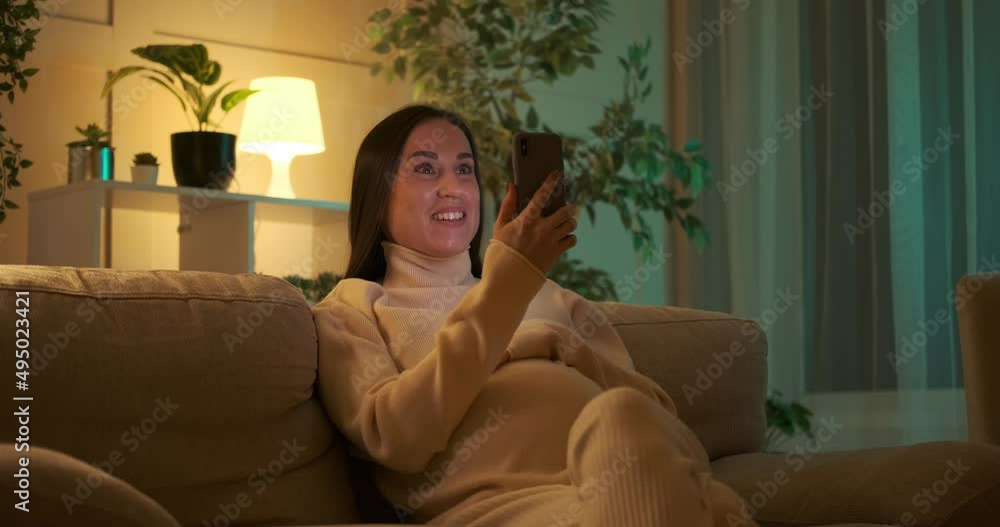 Pregnant woman video chatting on mobile phone and caressing her belly at night Pregnant woman video chatting on mobile phone and caressing her belly at night