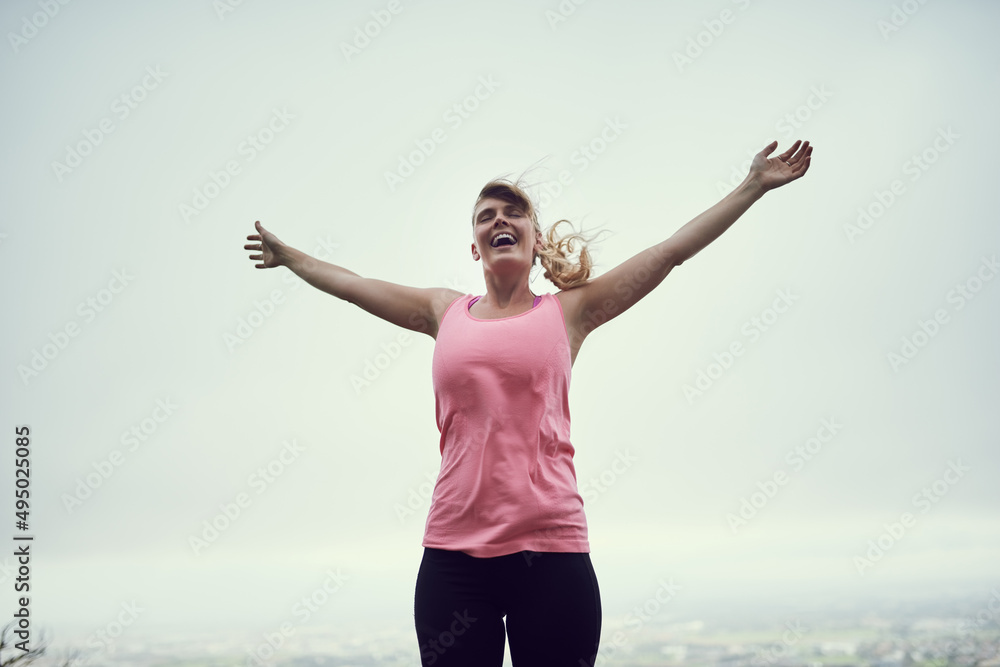 Feeling fit and free. Shot of a happy young woman feeling free while out for a run in the city.