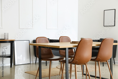 Interior of modern dining room with table and black armchairs