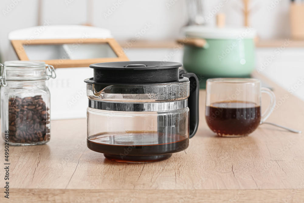 Coffee machine pot with hot beverage on wooden counter in kitchen, closeup Coffee machine pot with hot beverage on wooden counter in kitchen, closeup
