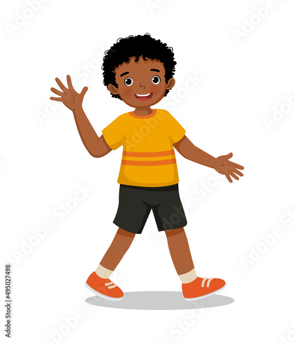 cute little African boy walking on the road greeting waving hand and smiling