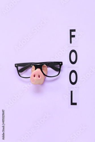 Composition with eyeglasses, pig nose and word FOOL on color background. April Fools Day celebration