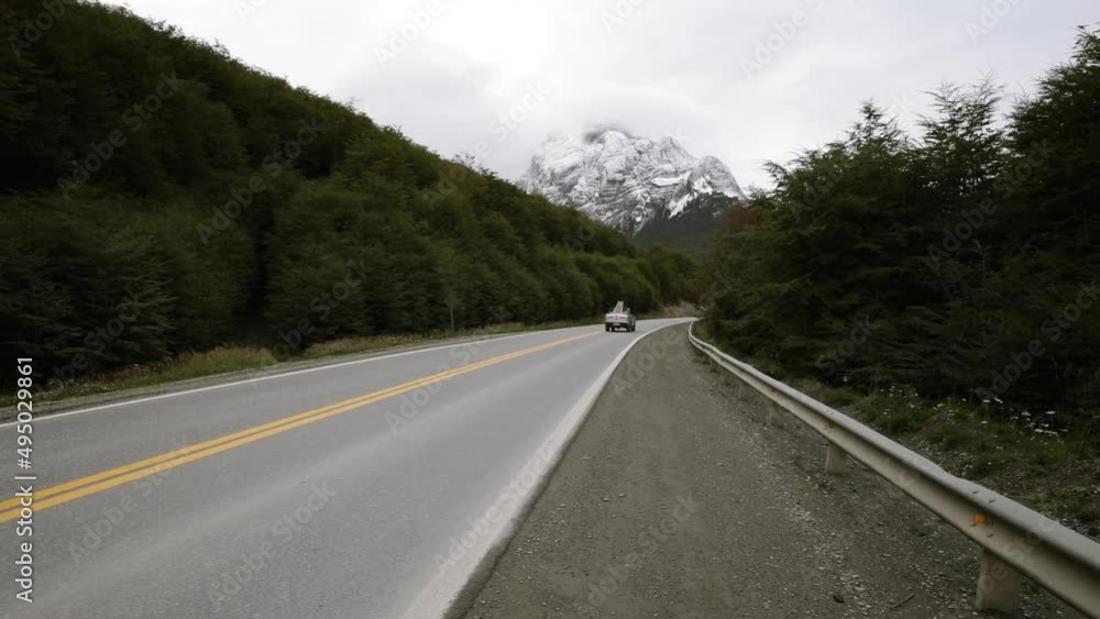 Pick up truck driving away along the road across the woods and mountains. Pick up truck driving away along the road across the woods and mountains.