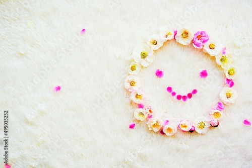 起毛した素材の白布の背景にたくさんの赤と白の梅の花で作った笑顔のフェイスマーク photo